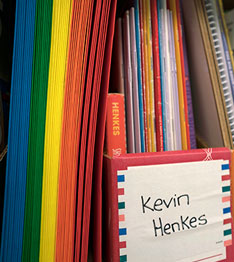 Box with the name Kevin Henkes on it and colorful papers and folders